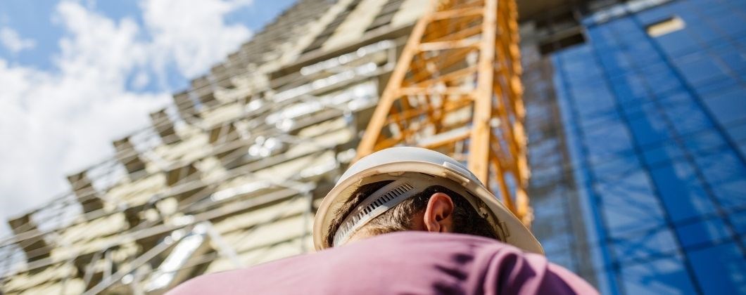 man with hard hat standing in front of scaffolding - insurance for construction professionals