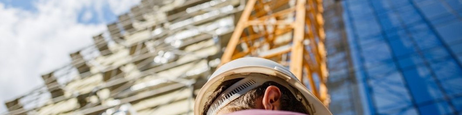 man with hard hat standing in front of scaffolding - insurance for construction professionals